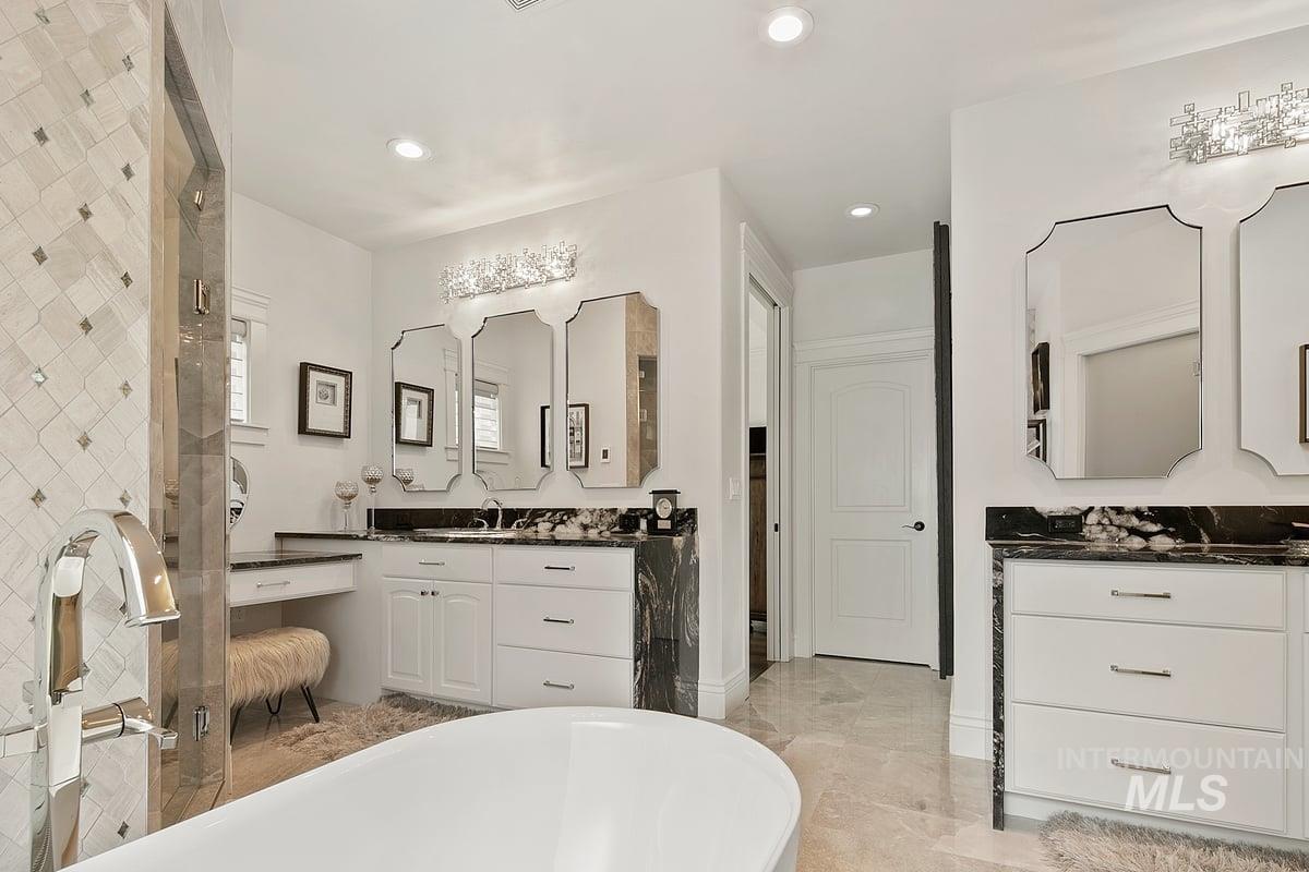 Bathroom with a freestanding tub, vanity, and recessed lighting