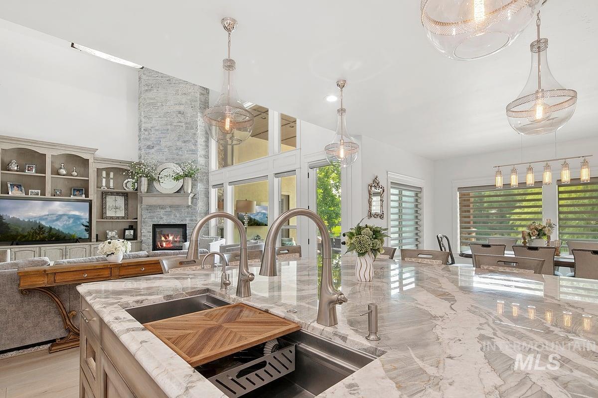 Kitchen featuring light stone countertops, healthy amount of natural light, decorative light fixtures, a stone fireplace, and a high ceiling
