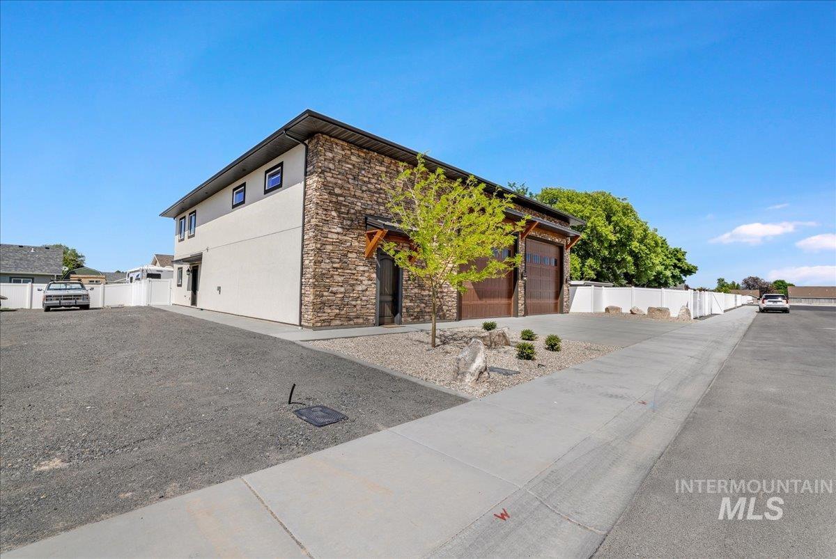 View of front of home featuring stone siding, a garage, and stucco siding
