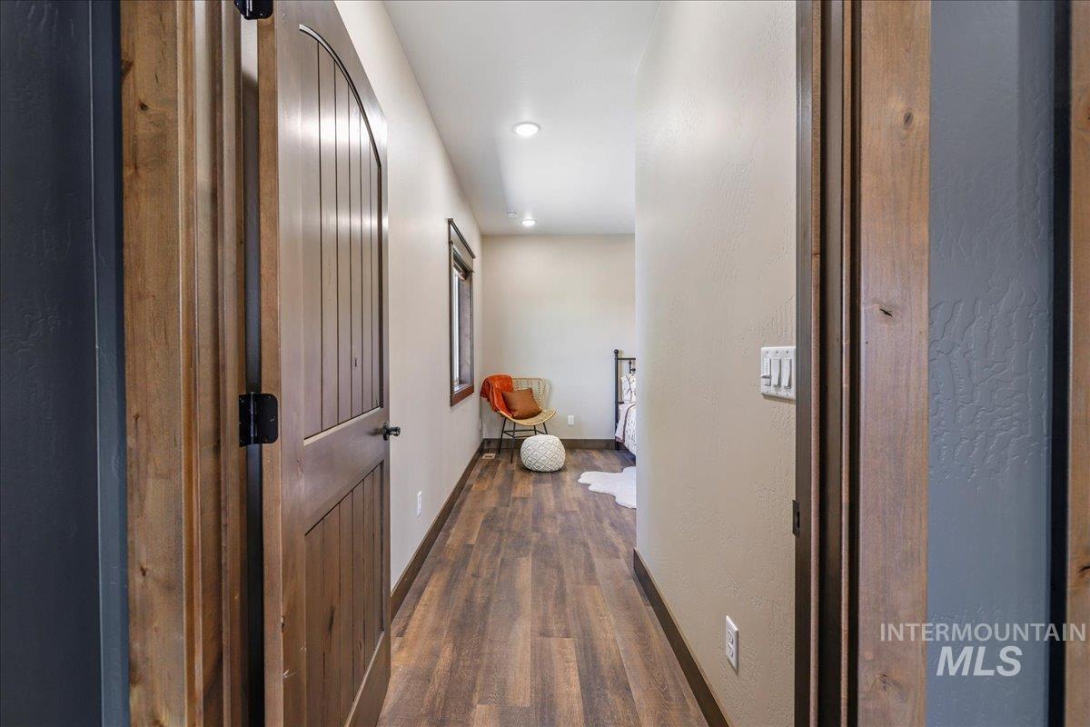 Hallway featuring dark wood-style flooring, recessed lighting, and a textured wall