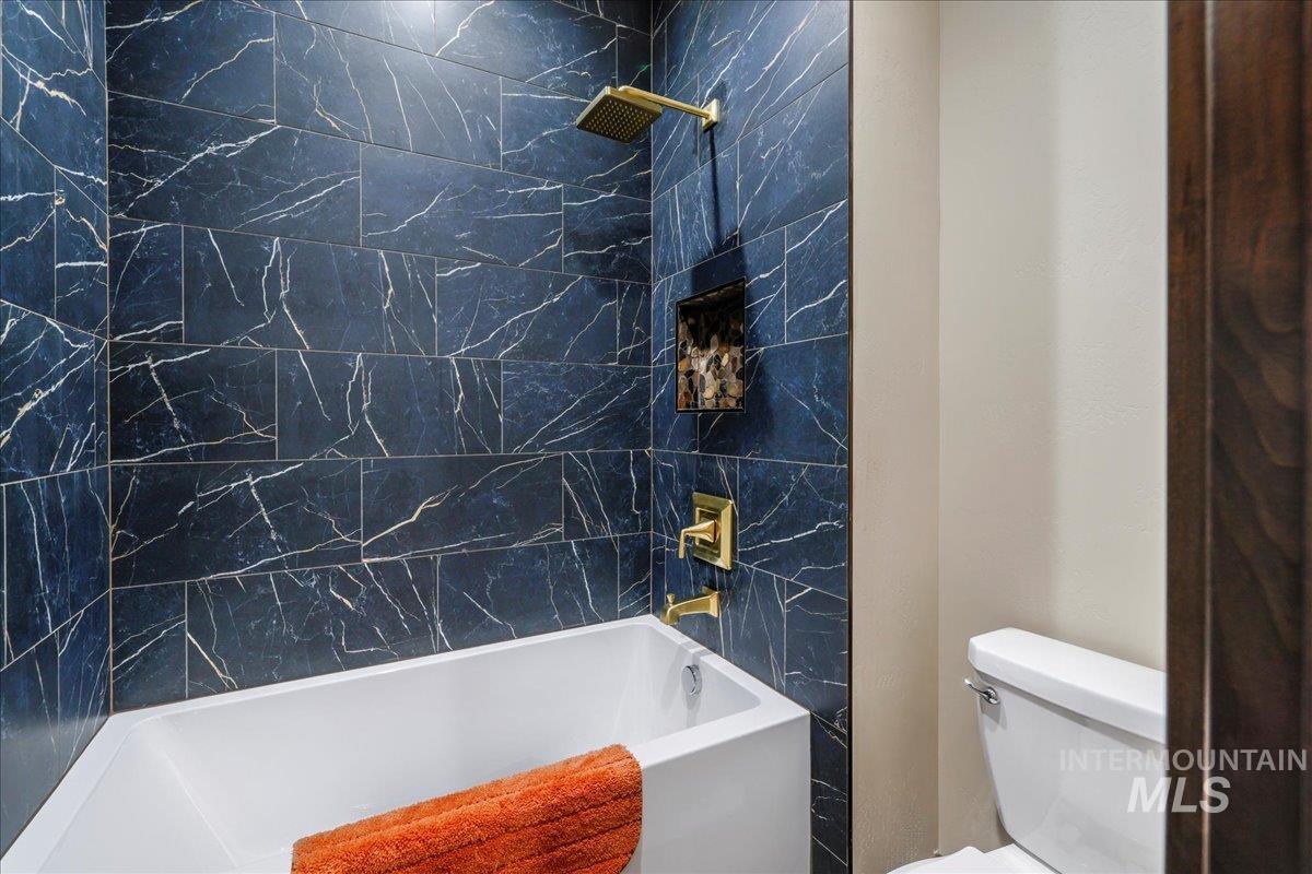 Bathroom featuring toilet and washtub / shower combination
