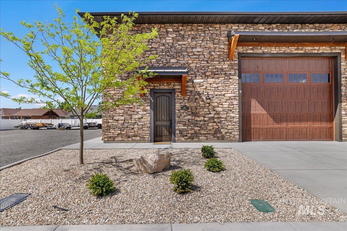 View of front of property with stone siding, driveway, and a garage