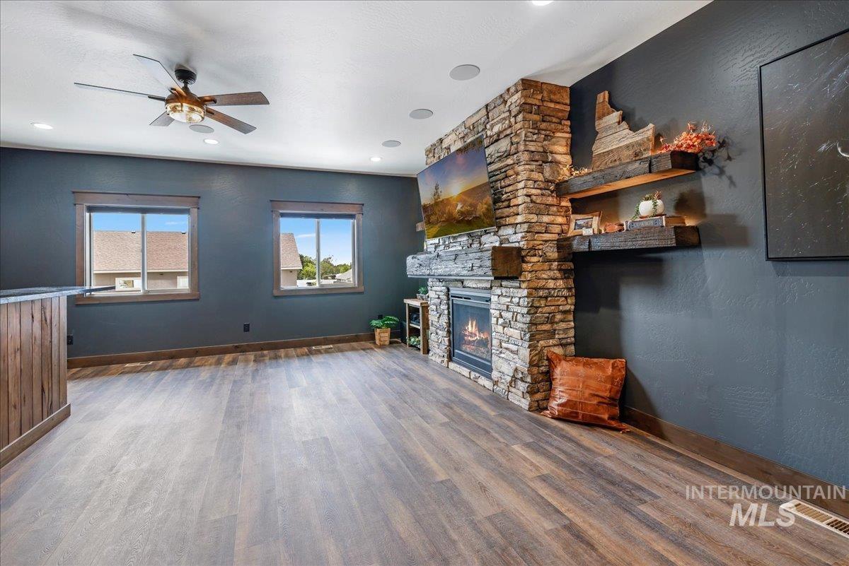 Unfurnished living room with wood finished floors, a fireplace, ceiling fan, a textured wall, and recessed lighting