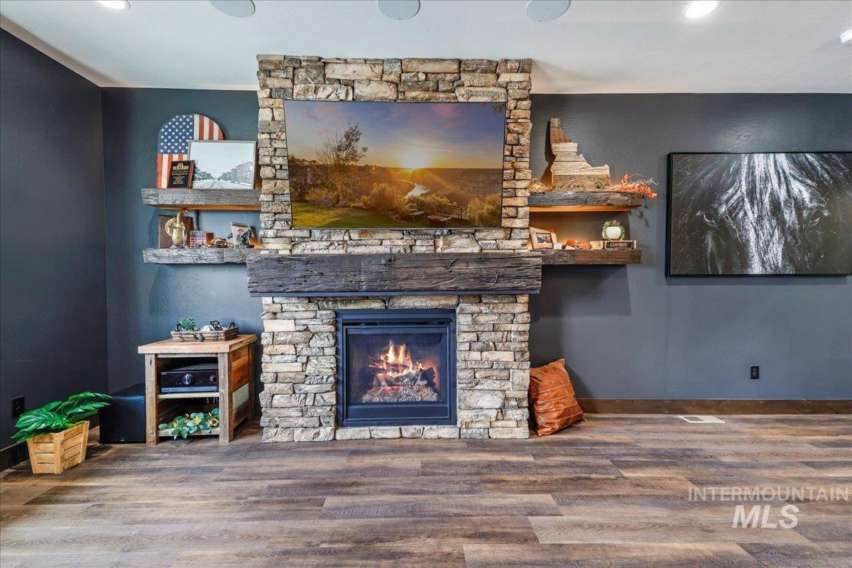 Living area featuring recessed lighting, a stone fireplace, and wood finished floors