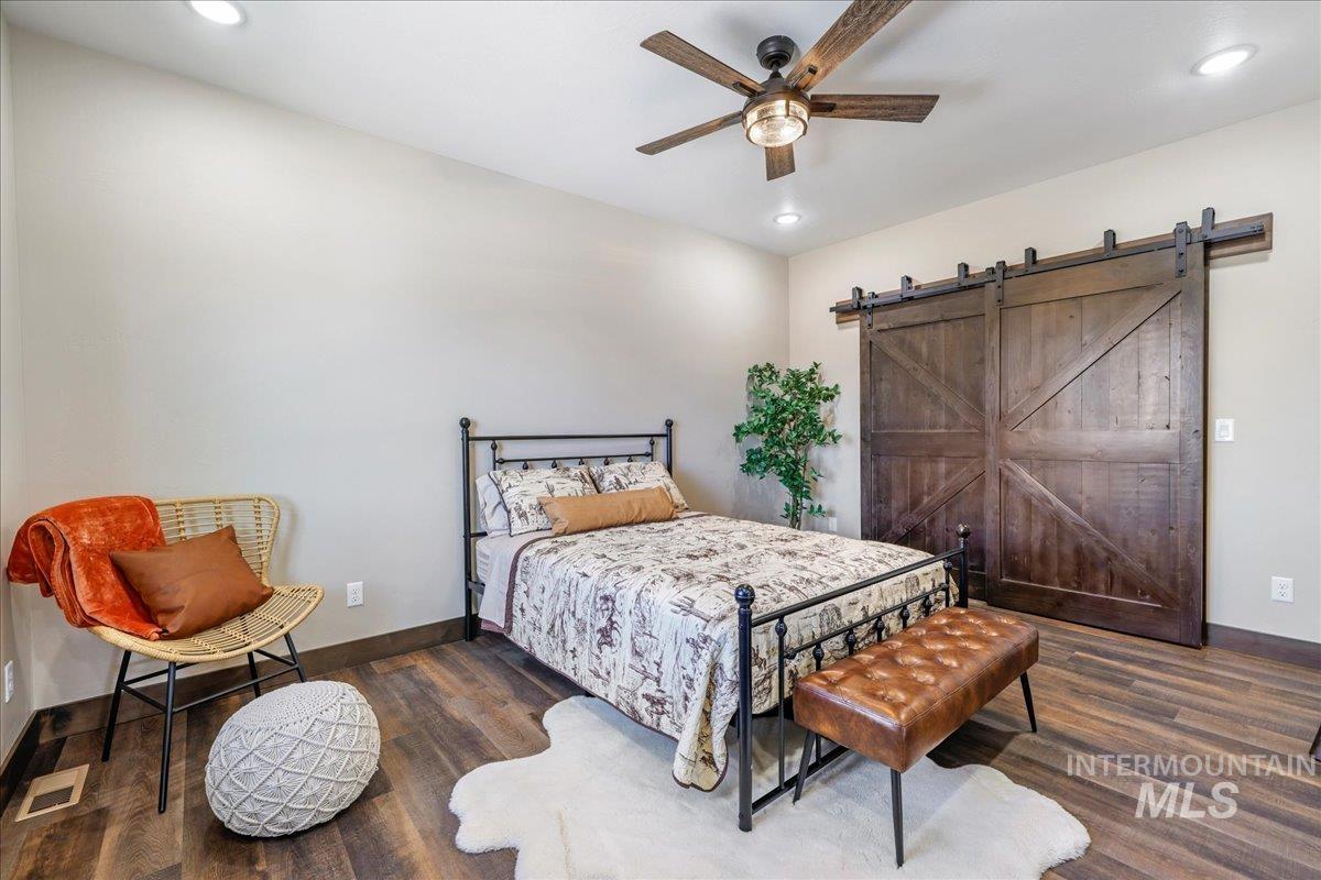 Bedroom featuring dark wood-style floors, recessed lighting, a ceiling fan, and a barn door
