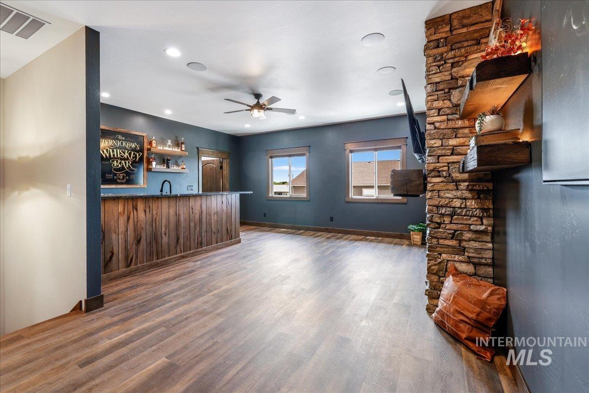 Unfurnished living room with wood finished floors, recessed lighting, wet bar, and a ceiling fan