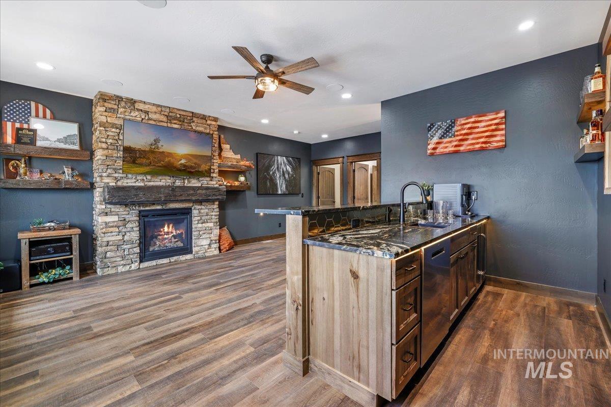Kitchen with a peninsula, dark stone counters, dark wood-style floors, a fireplace, and open floor plan