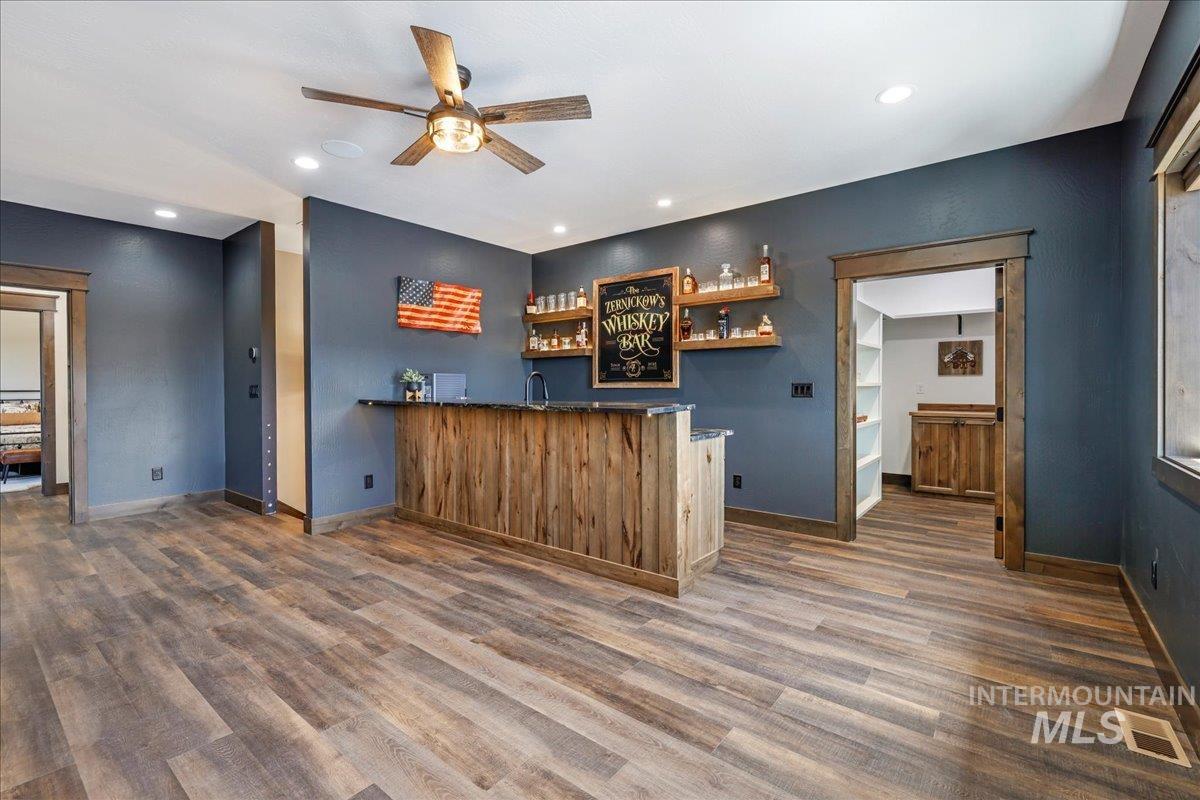 Indoor wet bar with open shelves, dark countertops, recessed lighting, dark wood-style floors, and ceiling fan