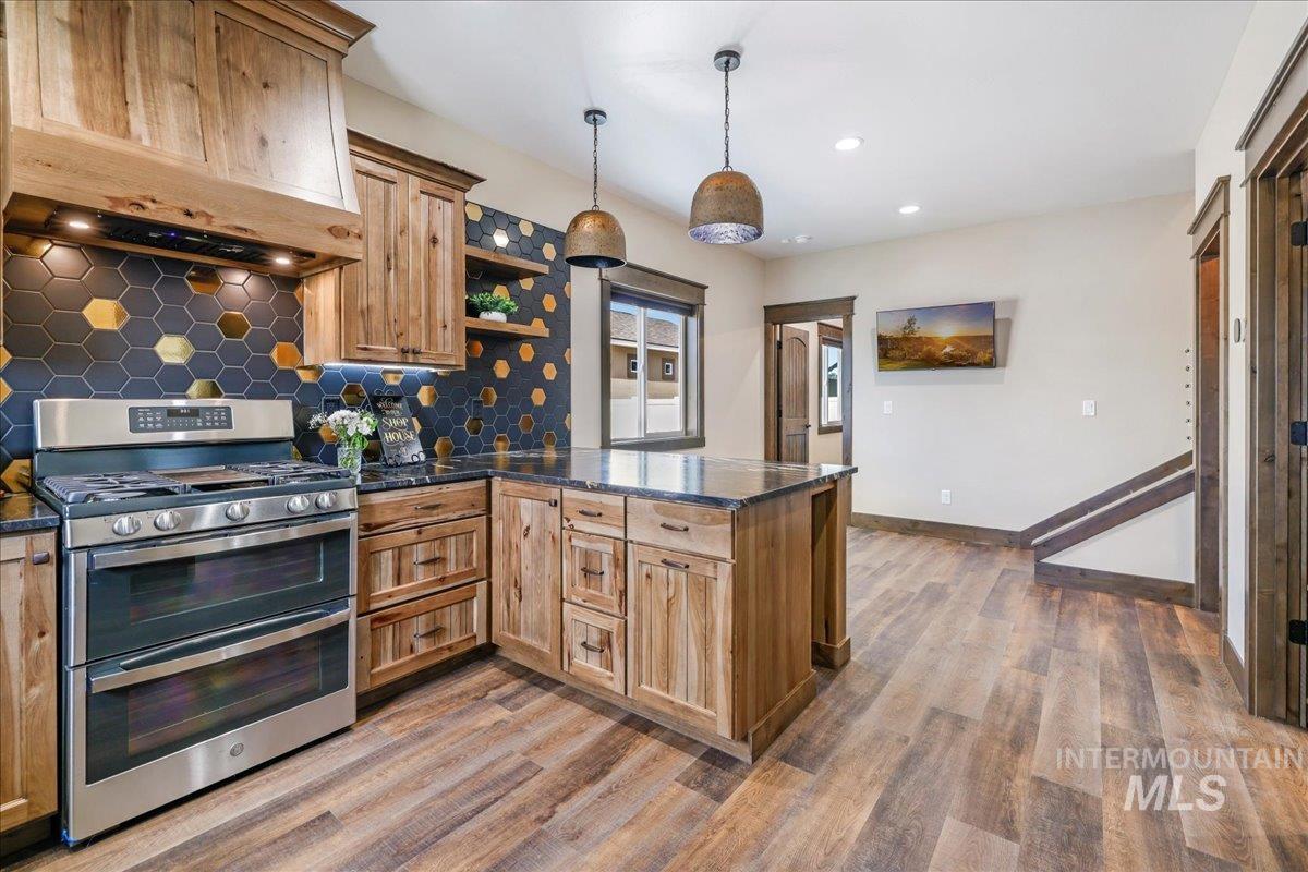 Kitchen with range with two ovens, premium range hood, a peninsula, open shelves, and tasteful backsplash