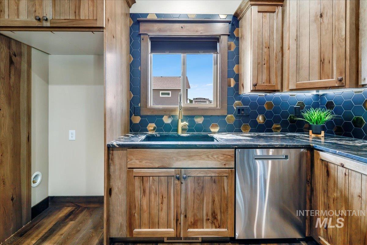 Kitchen with dishwasher, backsplash, dark stone counters, and dark wood-style flooring
