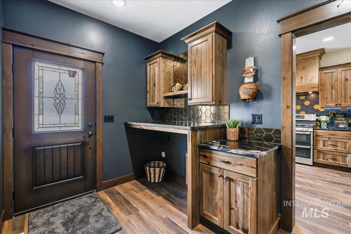 Kitchen featuring backsplash, light wood-style floors, range with two ovens, a textured wall, and brown cabinets