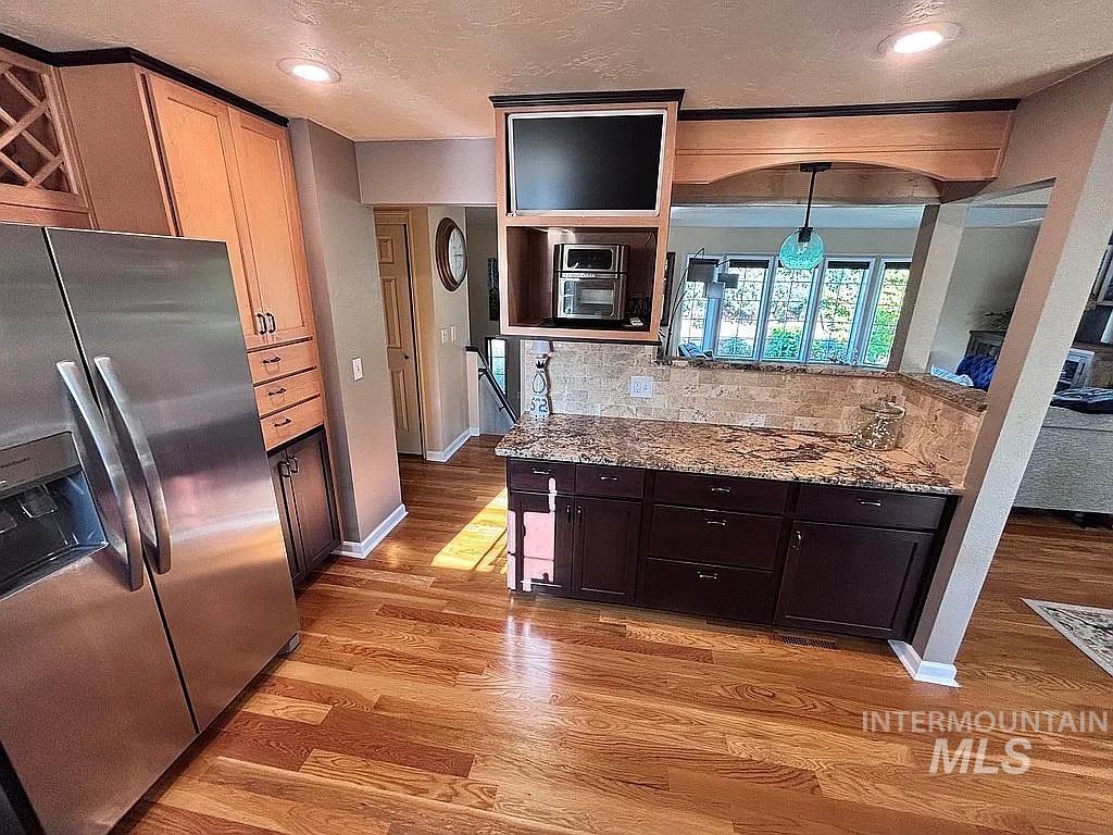 Kitchen featuring wood-finish flooring, stainless steel refrigerator, and recessed lighting