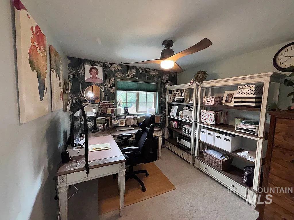 Well-lit room featuring a window with blinds, ceiling fan with integrated lighting, and two multi-level shelving units with drawer storage