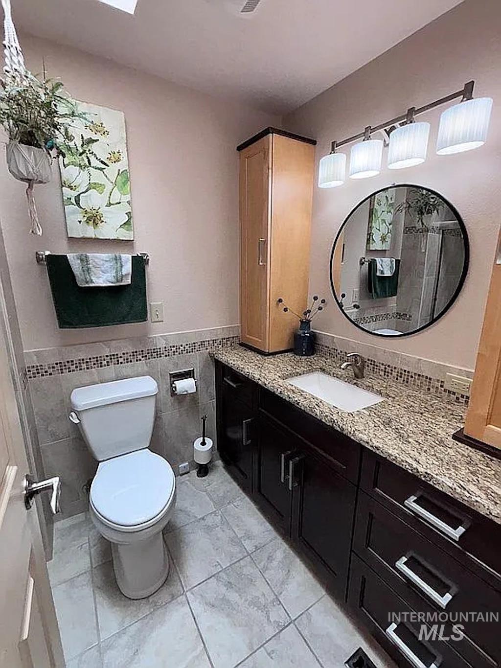 Bathroom featuring a vanity with granite-style countertop, integrated sink, and dark wood-finish cabinetry
