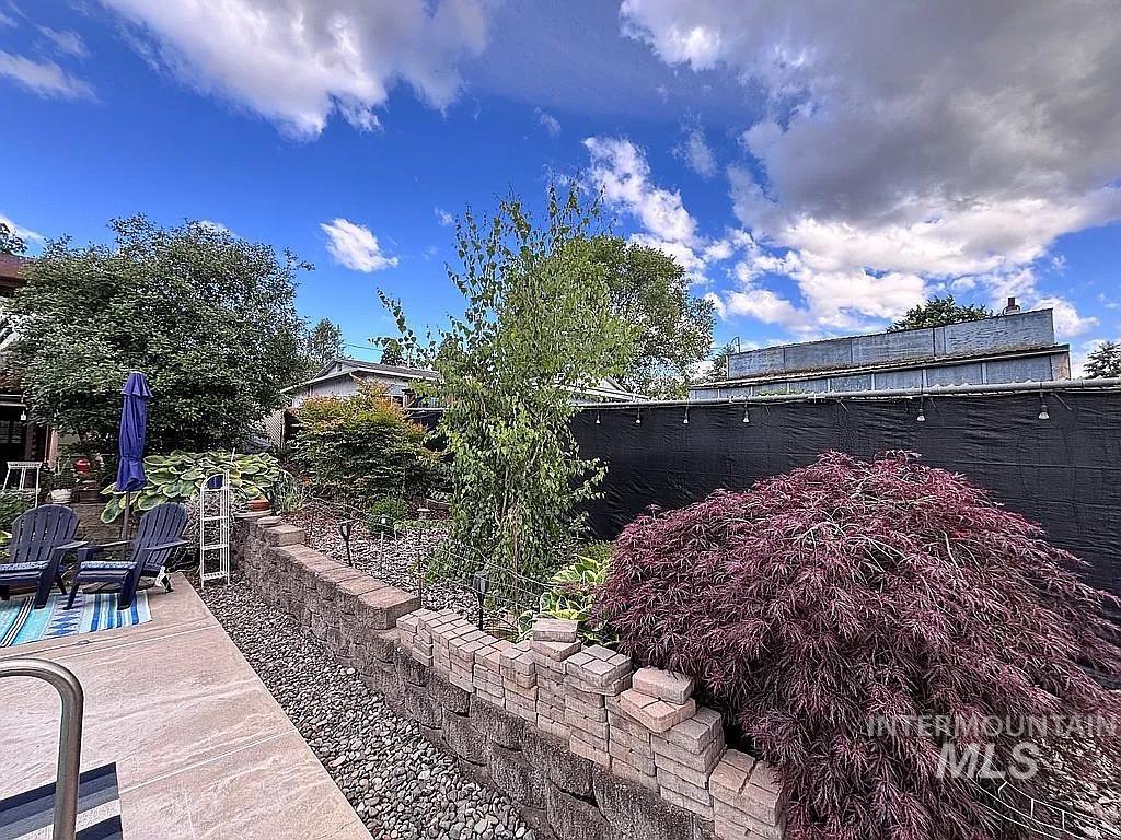 Outdoor living area featuring a stone tile patio with a striped rug and a stone retaining wall