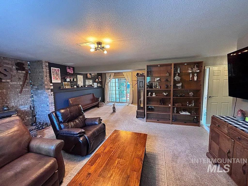 Spacious room featuring a prominent brick column, carpet flooring, and a contemporary ceiling light fixture