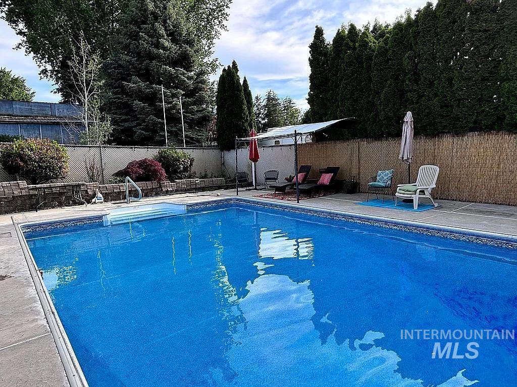 In-ground swimming pool with integrated steps, surrounded by a concrete patio