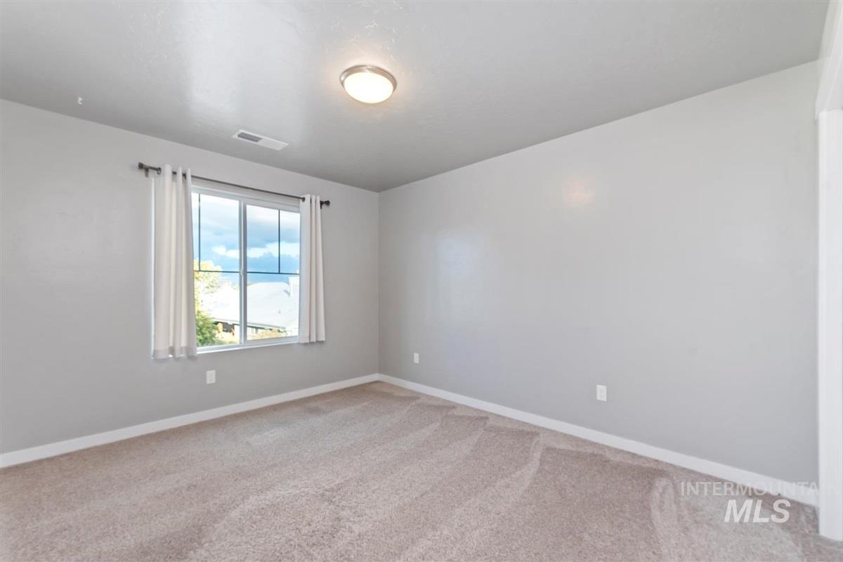 Empty room with light colored carpet and baseboards