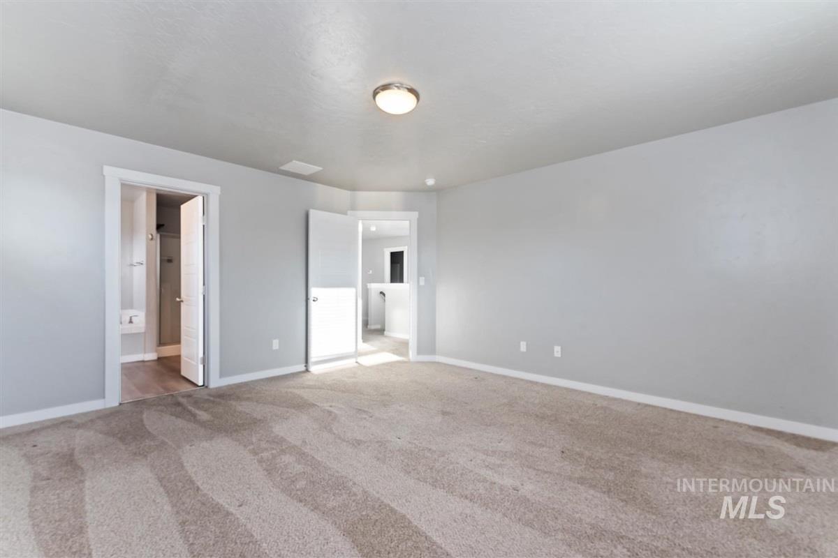 Unfurnished bedroom featuring light colored carpet and ensuite bathroom