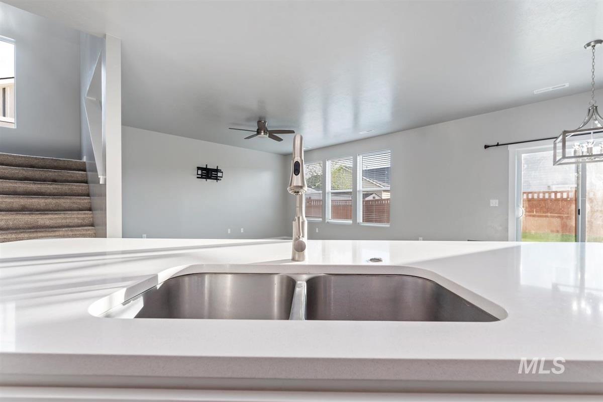 Kitchen featuring pendant lighting, light stone countertops, and a ceiling fan