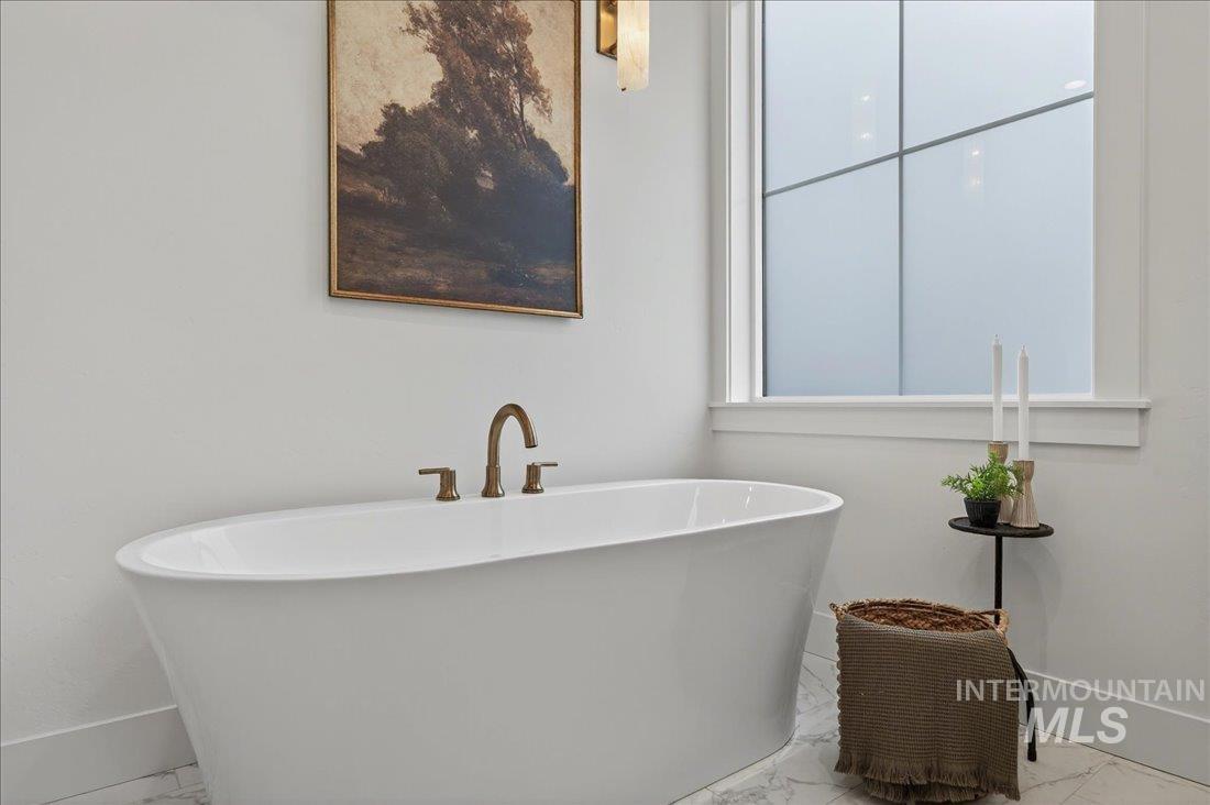 Full bathroom featuring marble finish floors and a soaking tub