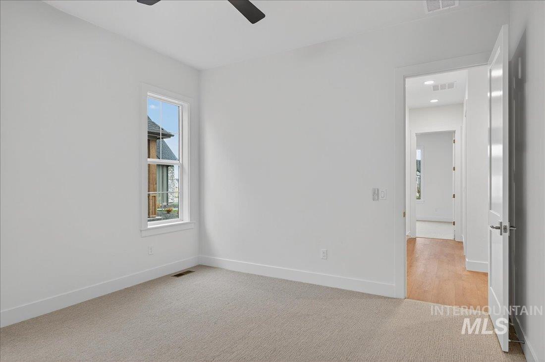 Empty room with light colored carpet and ceiling fan