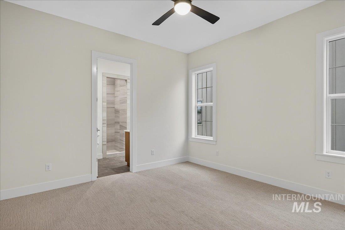 Unfurnished bedroom with light carpet, ceiling fan, and connected bathroom