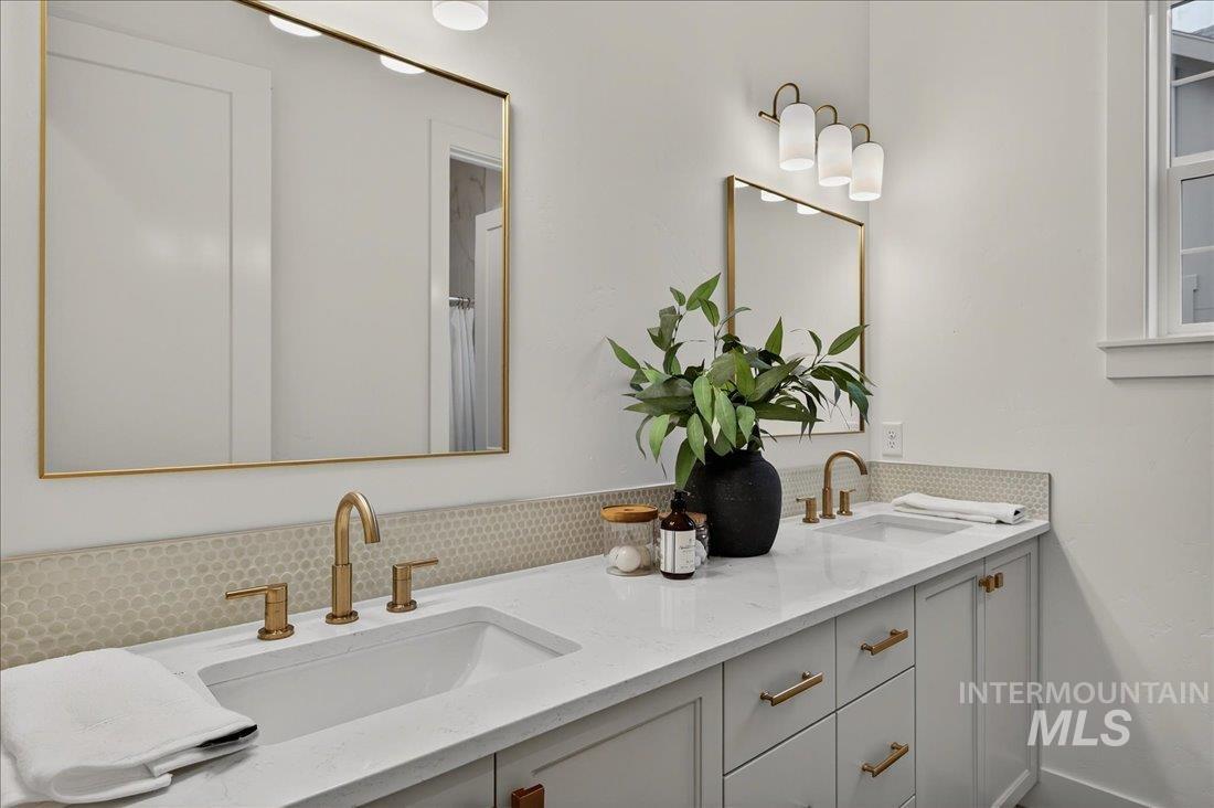 Bathroom featuring double vanity, tasteful backsplash, and a shower with curtain