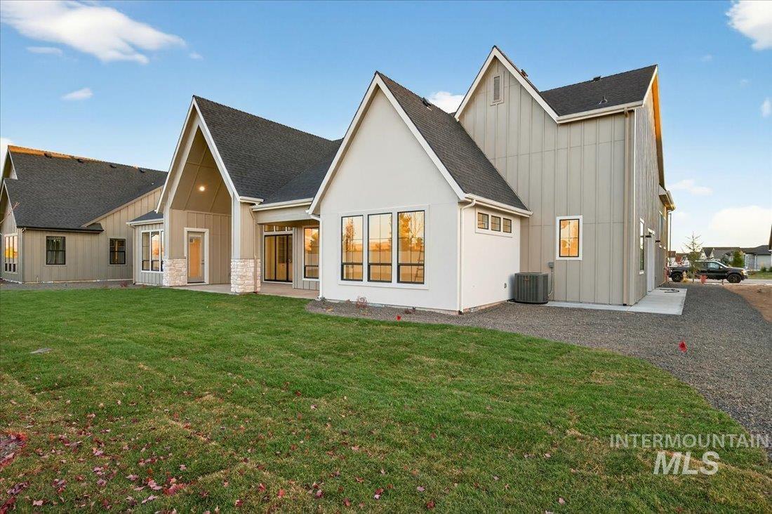 Back of house featuring board and batten siding, a patio area, a yard, and roof with shingles