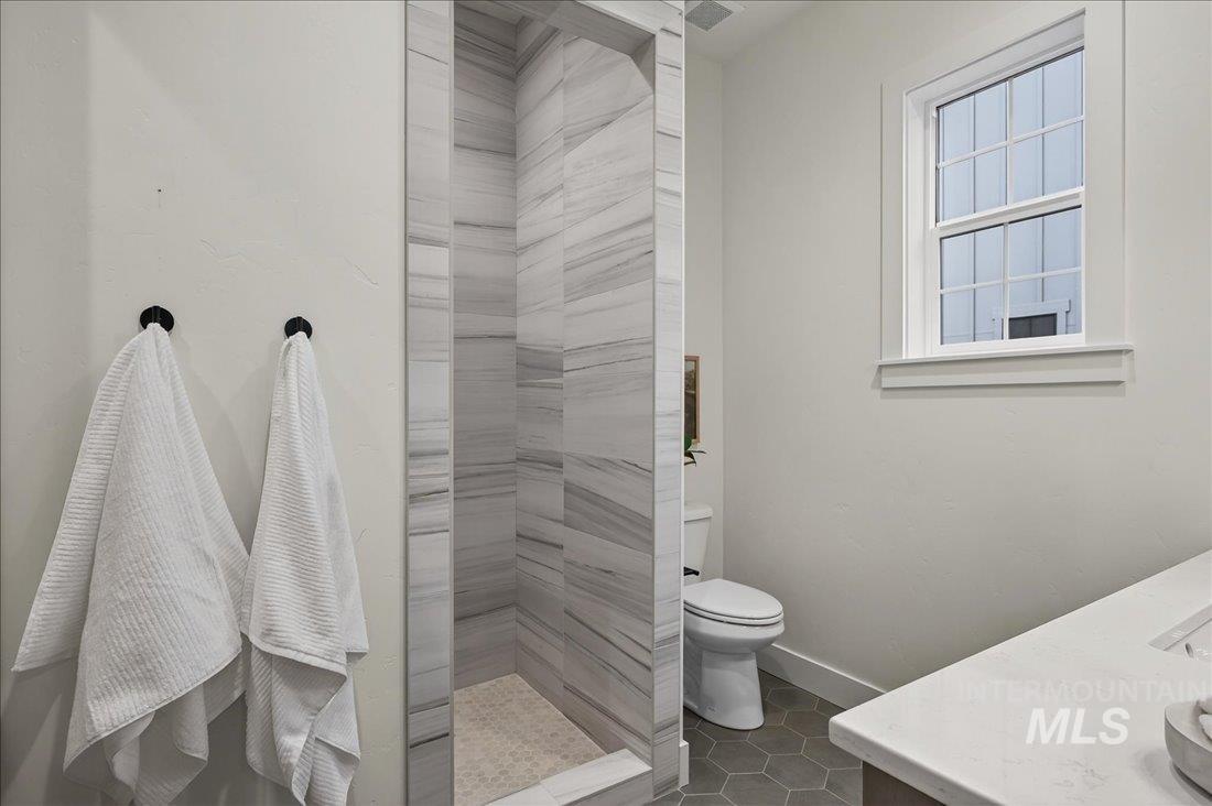 Bathroom featuring vanity, a stall shower, and dark tile patterned floors