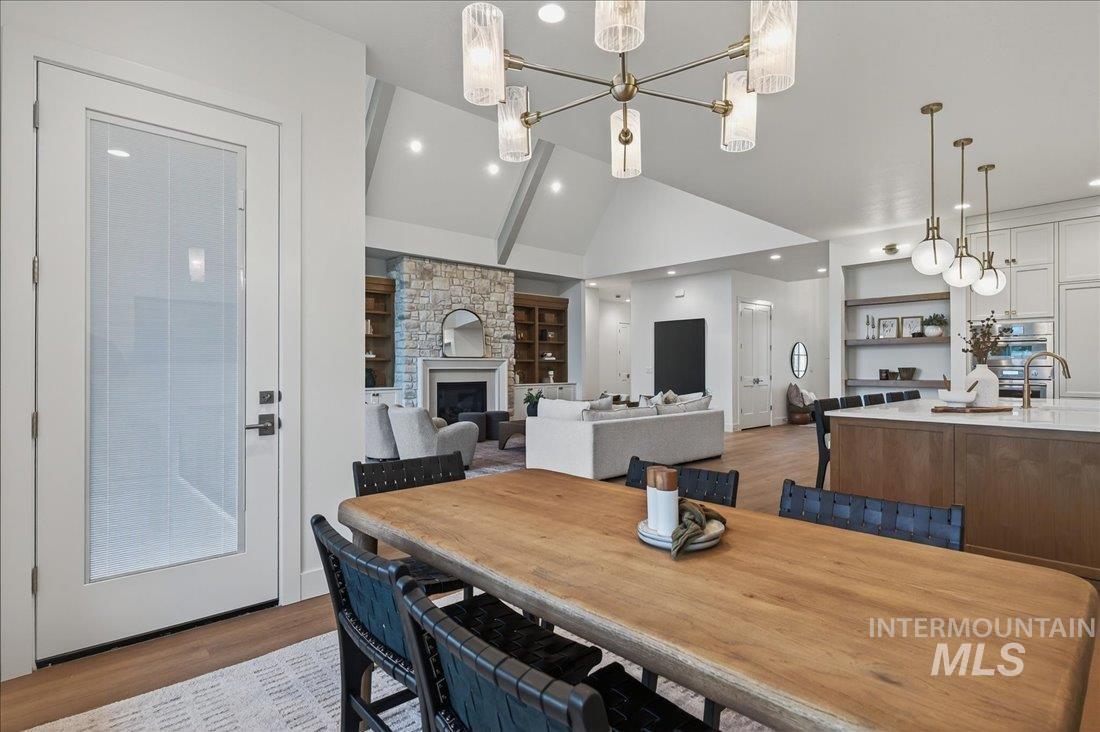 Dining room featuring vaulted ceiling, a fireplace, built in features, dark wood-style floors, and a chandelier
