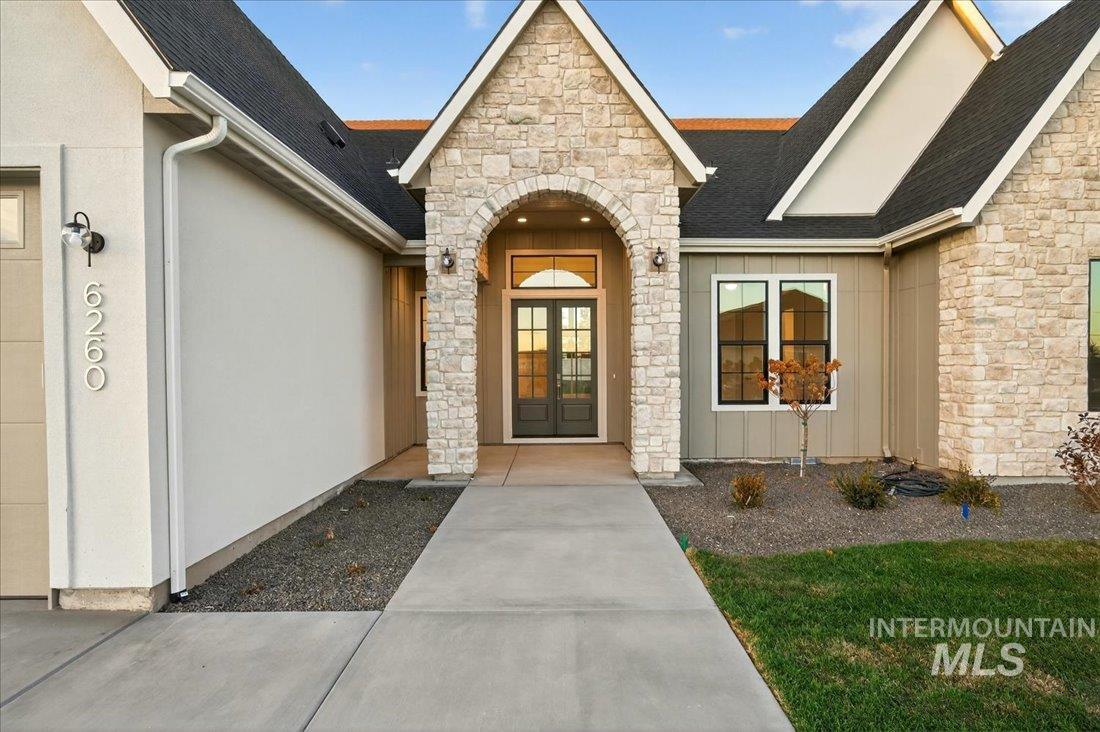 Property entrance with stone siding, roof with shingles, board and batten siding, and french doors