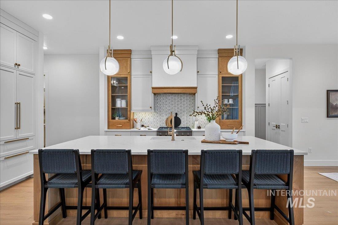 Kitchen featuring white cabinets, light wood-style flooring, hanging light fixtures, and recessed lighting