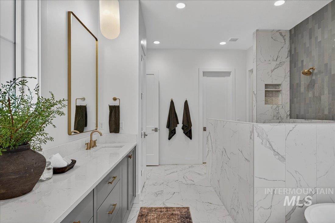 Full bath featuring a marble finish shower, vanity, light marble finish flooring, and recessed lighting