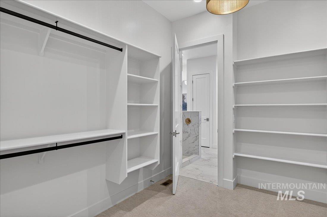 Walk in closet featuring light carpet and light marble finish floors