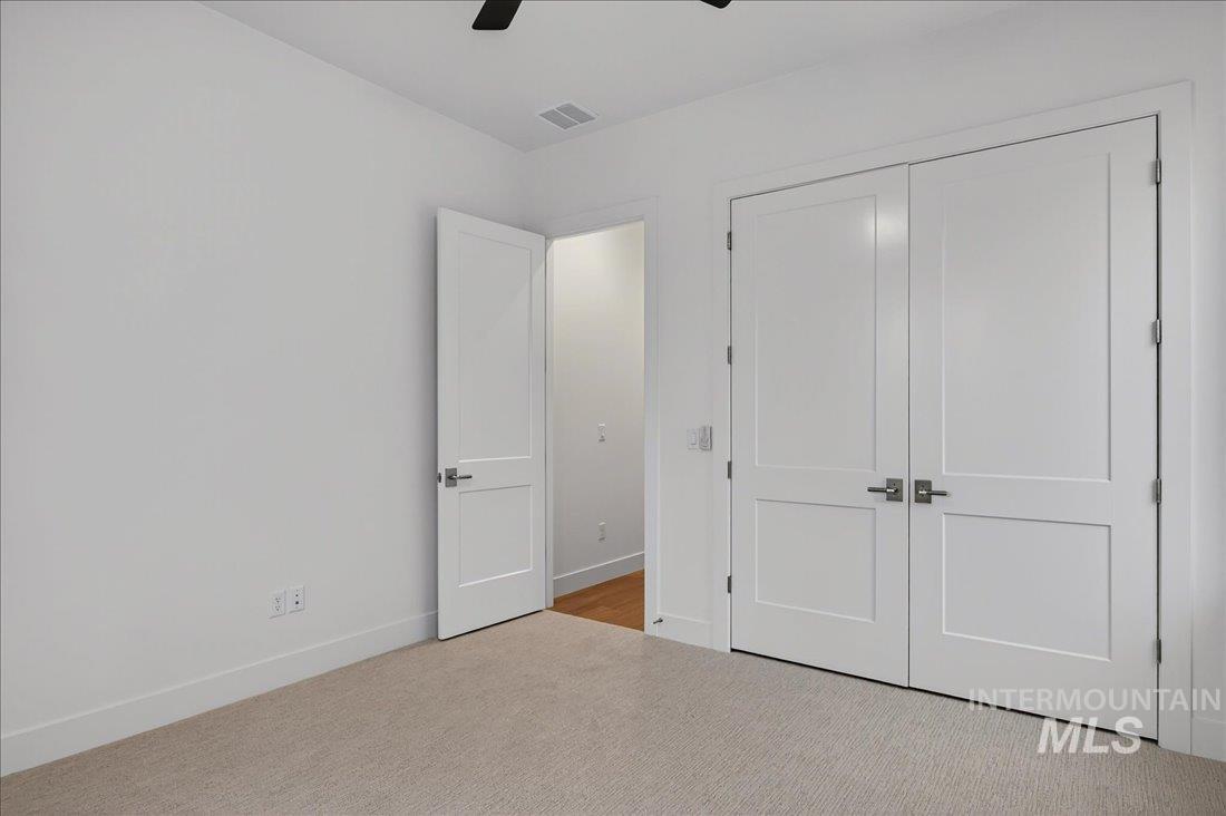 Unfurnished bedroom featuring carpet, a closet, and a ceiling fan