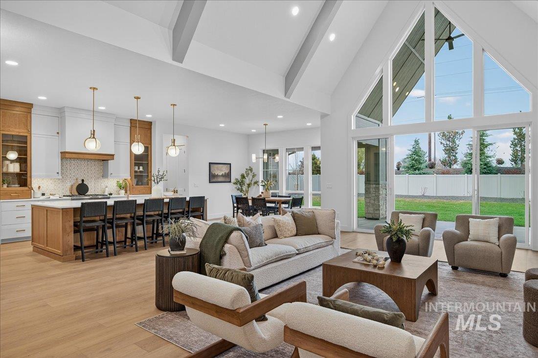 Living room with high vaulted ceiling, light wood finished floors, and beamed ceiling