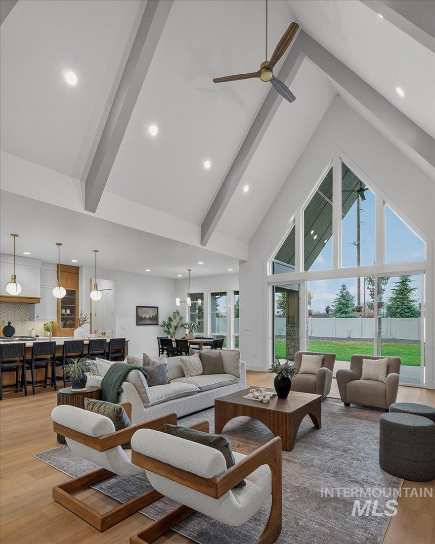 Living room featuring light wood-type flooring, high vaulted ceiling, beamed ceiling, recessed lighting, and a ceiling fan