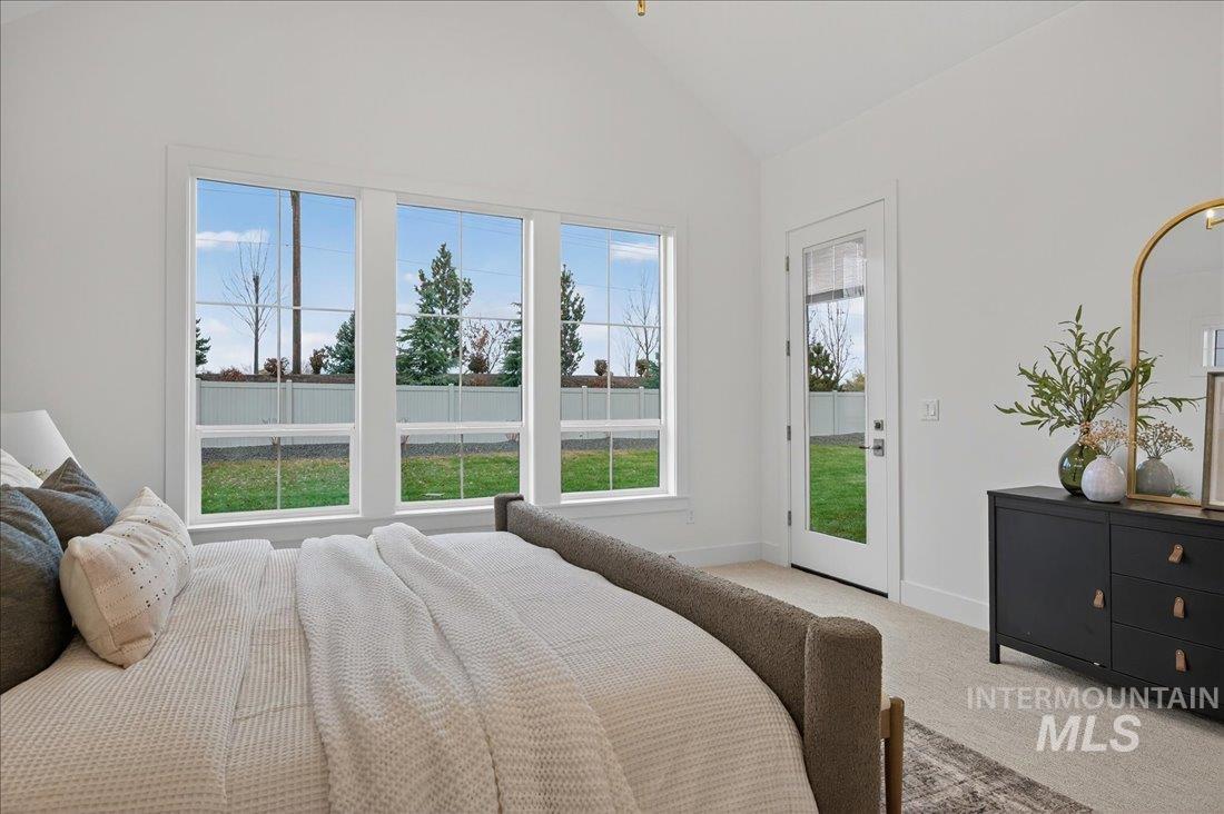 Carpeted bedroom featuring vaulted ceiling and access to outside