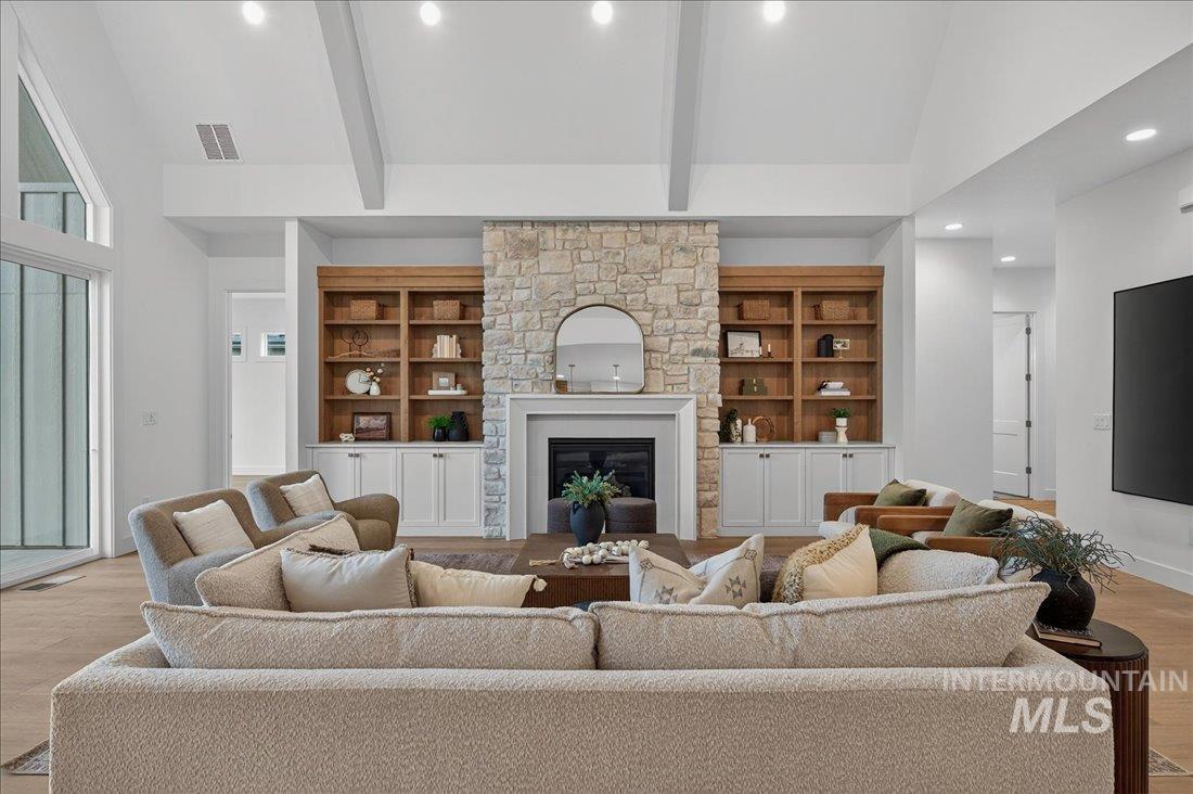 Living room with light wood-style floors, recessed lighting, a fireplace, beam ceiling, and built in shelves