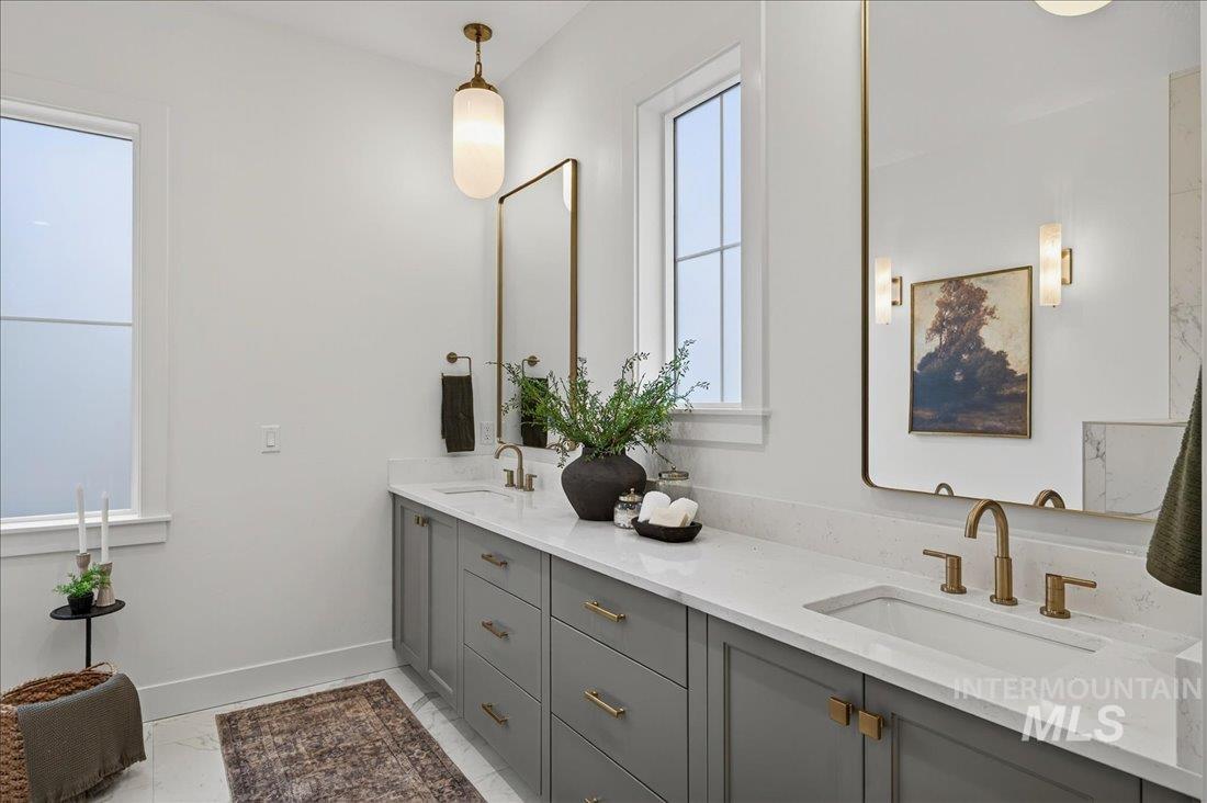 Full bathroom featuring double vanity and light marble finish flooring