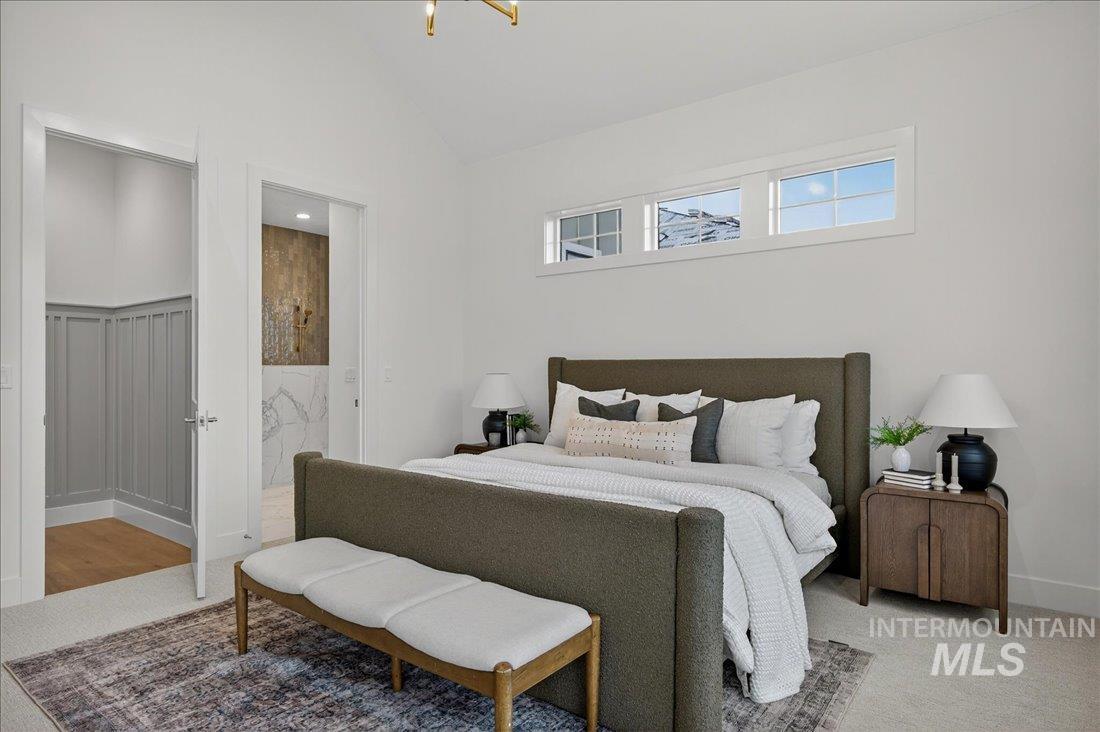 Carpeted bedroom featuring lofted ceiling and ensuite bath