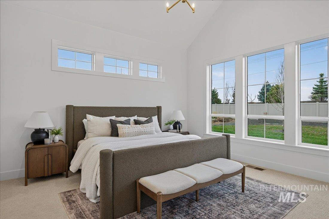 Bedroom featuring light carpet, multiple windows, high vaulted ceiling, and a chandelier