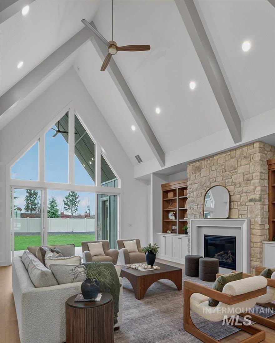Living area with high vaulted ceiling, built in shelves, beam ceiling, a glass covered fireplace, and recessed lighting