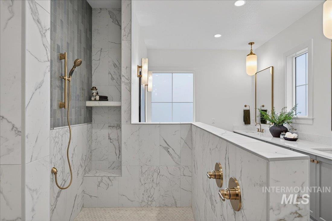 Full bathroom with a marble finish shower, double vanity, healthy amount of natural light, and recessed lighting