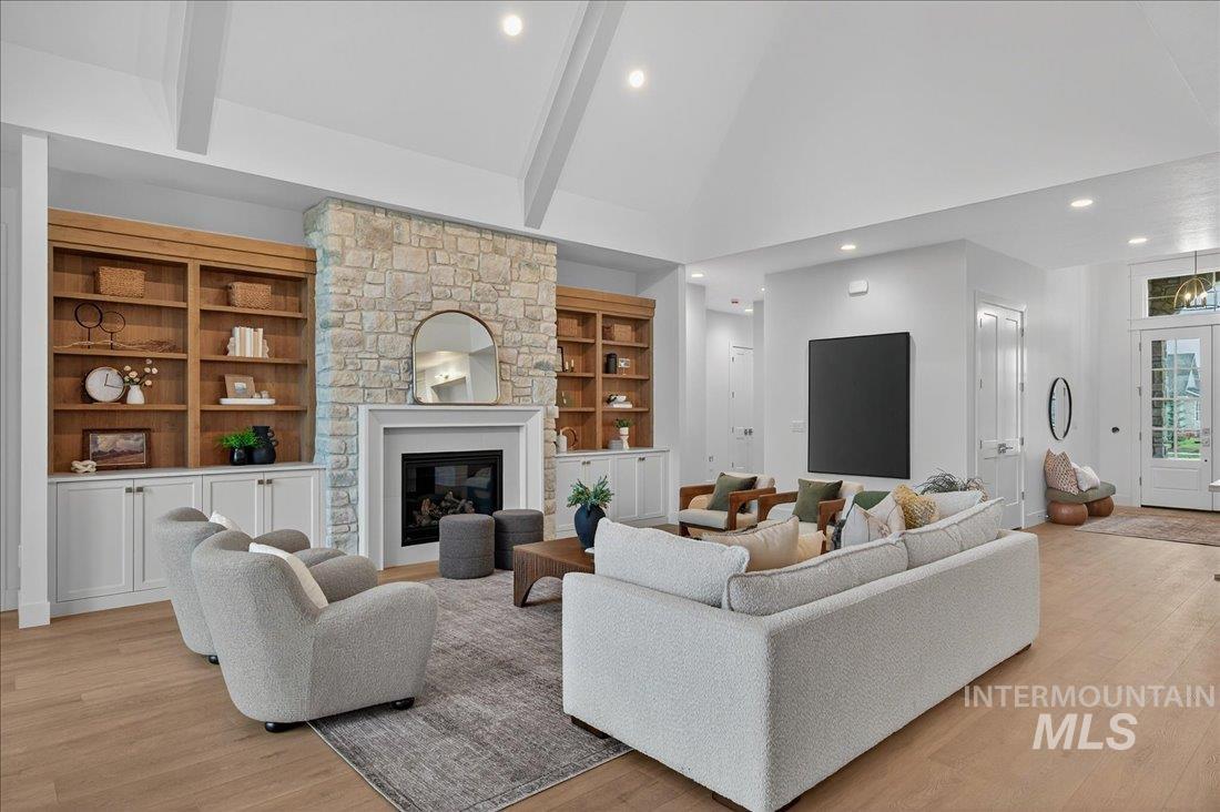 Living area with high vaulted ceiling, light wood-style floors, recessed lighting, built in shelves, and a fireplace