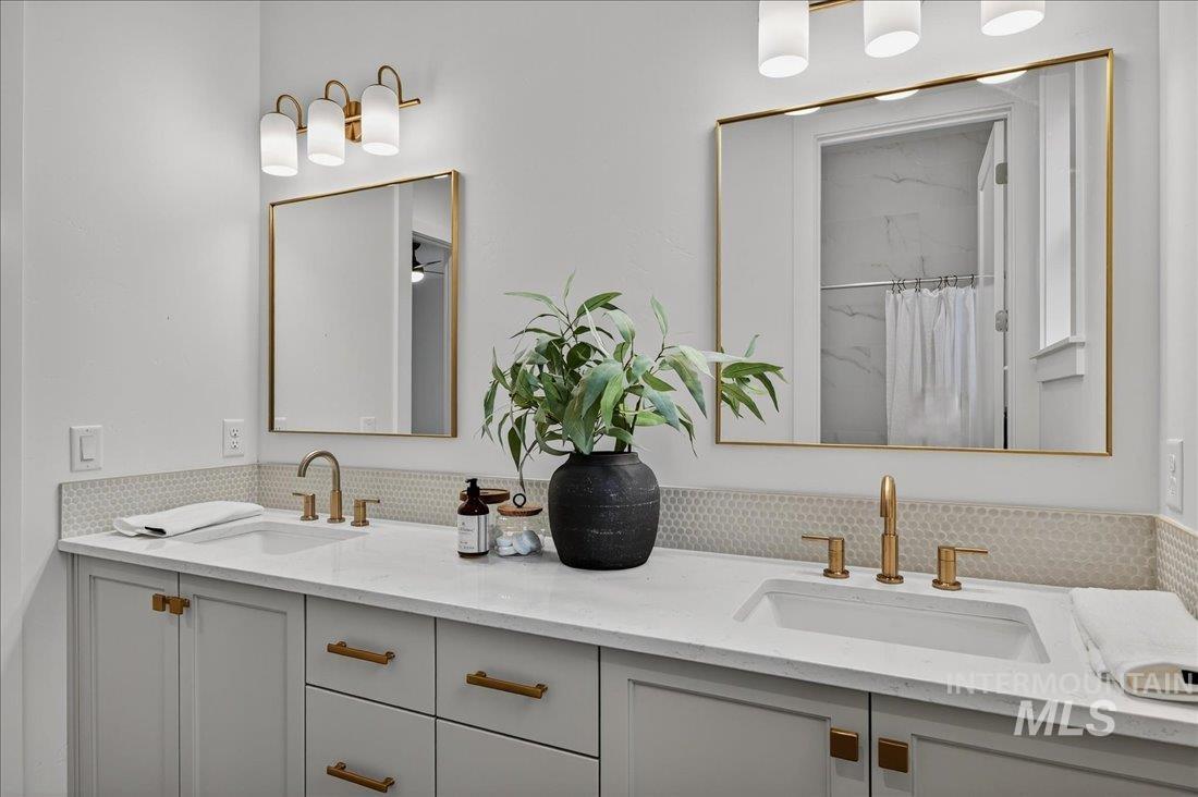 Full bath with a marble finish shower and double vanity