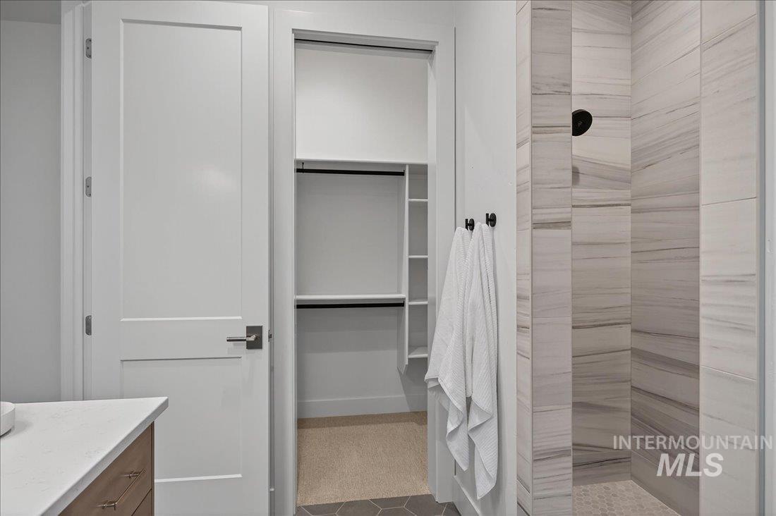 Full bath with vanity, a tile shower, and a walk in closet