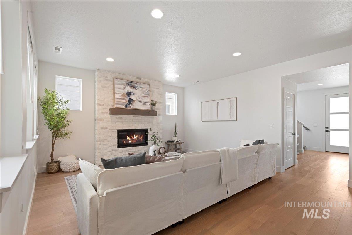 Living area featuring light wood-style flooring, a textured ceiling, recessed lighting, and a fireplace