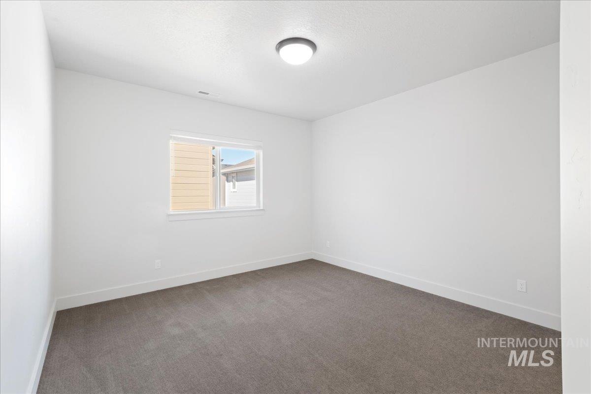 Carpeted spare room featuring baseboards and a textured ceiling